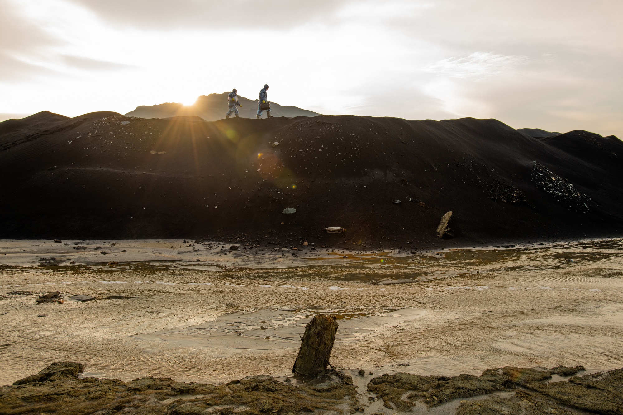 Tiny silhouettes of two contemporary researchers moving along hilltop